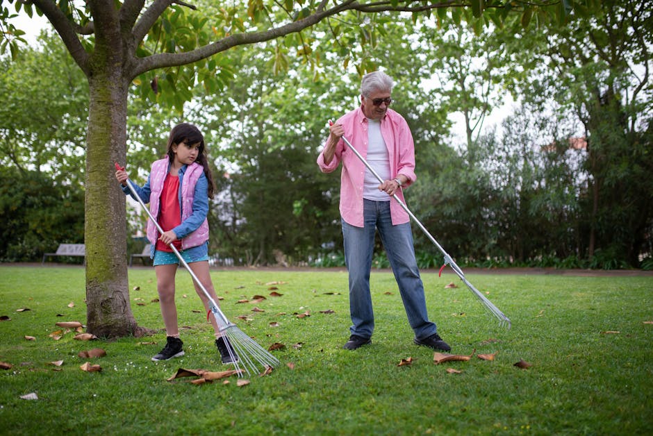 Warm family moment outdoors with grandfather and granddaughter raking leaves in a park.